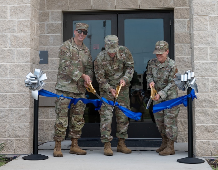 Senior leadership cut ribbon in front of new dorm facility.