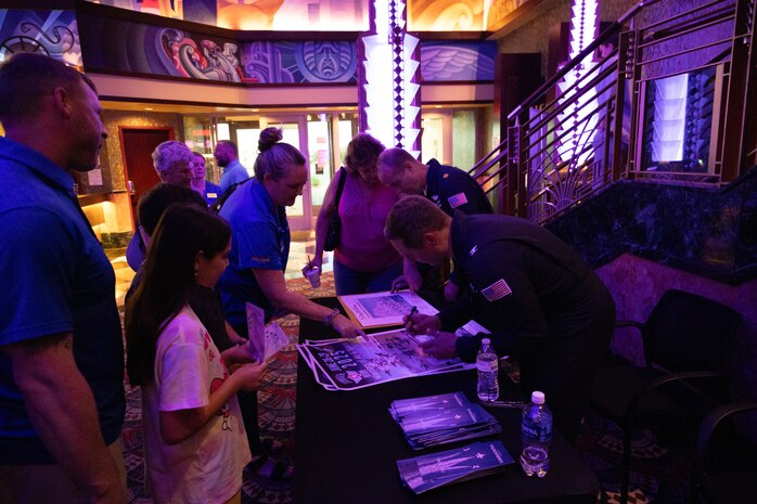 People signing movie posters.