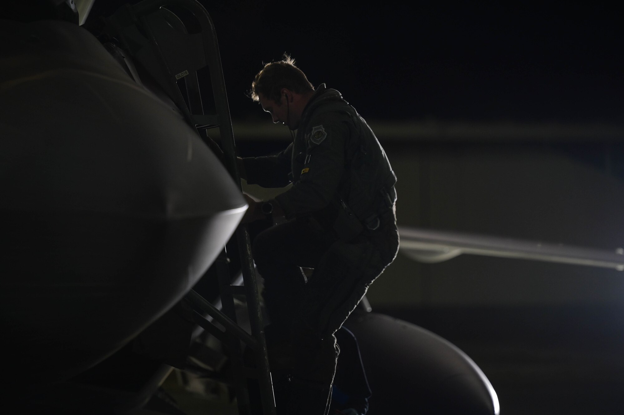 A pilot leaving the cockpit of a fighter jet down a ladder.