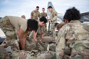 Servicemembers secure personnel on gurneys.