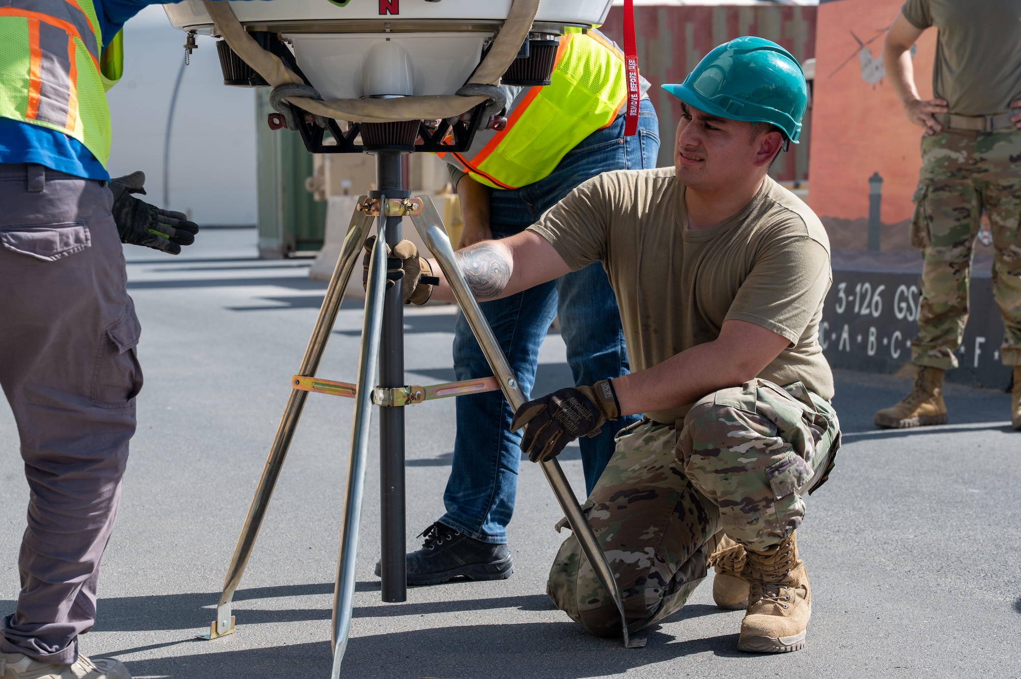Staff Sgt. Rodriguez kneels down right of frame beside a PDR in preparation for its installation