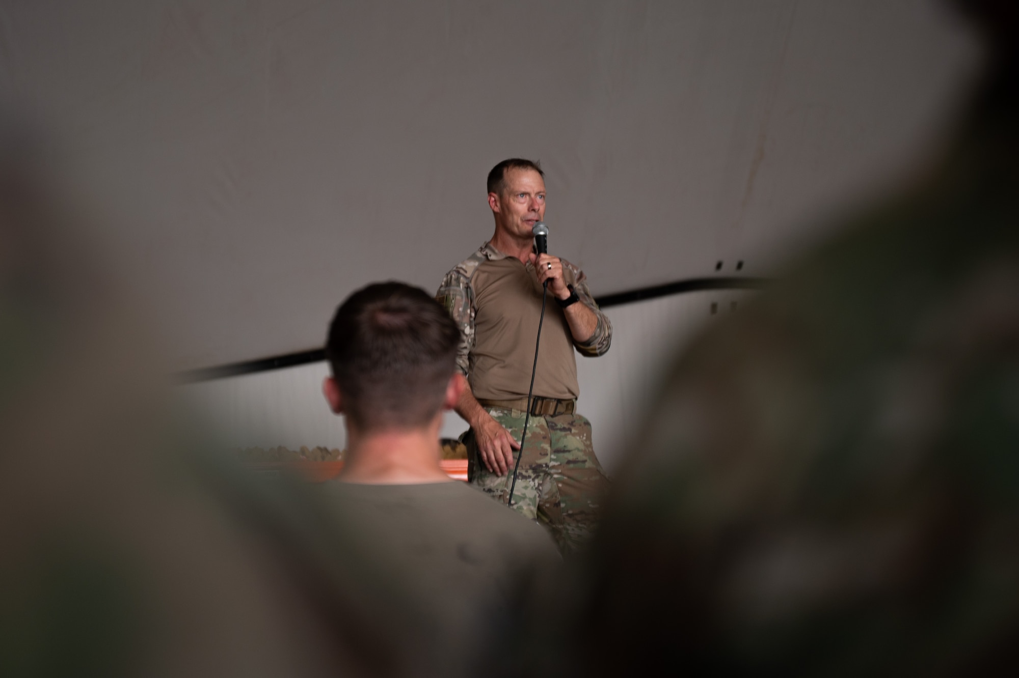 An Airman speaks while standing on a platform
