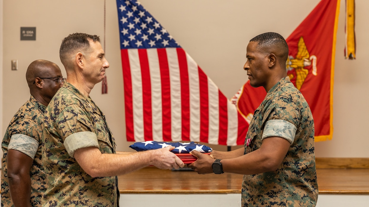 U.S. Marine Corps Col. Matthew Halton, left, the assistant chief of staff with G-1, 2d Marine Division, presents "Old Glory" along with several certificates to Master Sgt. Kirkland Levarity, a career counselor with 2d Marine Division, during Levarity's retirement ceremony on Camp Gilbert H. Johnson, North Carolina, July 25, 2025. The ceremony was held to honor Levarity’s 24 years of service to the Marine Corps. (U.S. Marine Corps photo by Lance Cpl. Dominic Trujillo)