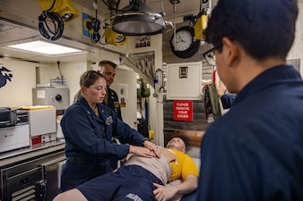 Hospital Corpsman 2nd Class Taryn Ditter from Troy, Missouri, left, demonstrates how to care for an abdomen wound as Lt. William Wright, middle, simulates an injury a mass casualty drill aboard the Arleigh Burke-class guided-missile destroyer USS Ralph Johnson (DDG 114) while operating in the Indian Ocean, July 14. Ralph Johnson is forward deployed and assigned to Destroyer Squadron (DESRON) 15, the Navy’s largest DESRON and the U.S. 7th fleet’s principal surface force. (U.S. Navy photo by Mass Communication Specialist 1st Class Hannah Fry)