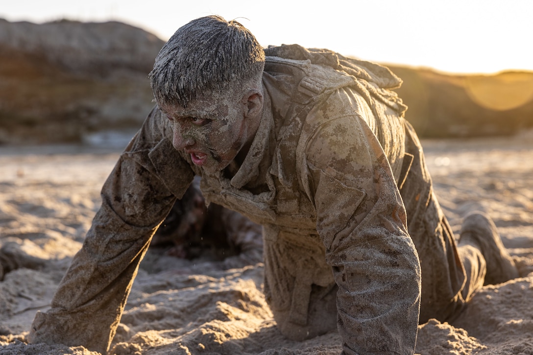 U.S. Marine Corps Cpl. Samuel L. Everett, a motor vehicle operator with 3d Low Altitude Air Defense Battalion, Marine Air Control Group 38, 3rd Marine Aircraft Wing, crawls through sand during the Martial Arts Instructor Course 99-25 culminating event at Marine Corps Base Camp Pendleton, California, July 9, 2025.