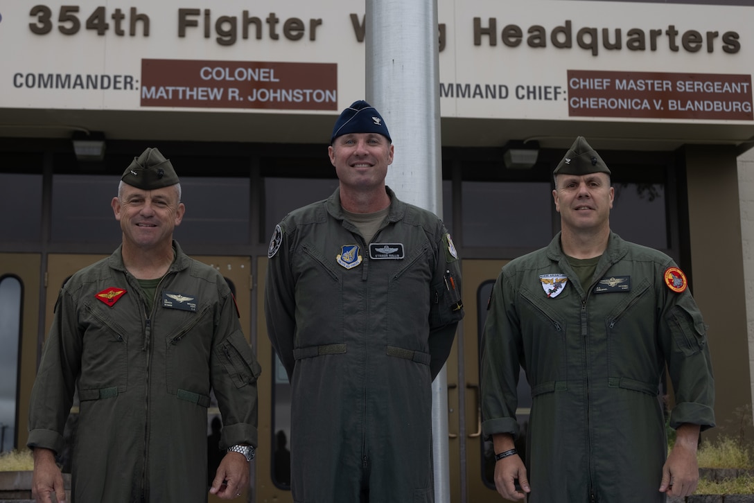 From left to right, U.S. Marine Corps Maj. Gen. James B. Wellons, the commanding general of 3rd Marine Aircraft Wing, U.S. Air Force Col. Michael S. Mullin, the deputy commander of 354th Fighter Wing and U.S. Marine Corps Col. Jarrod A. Devore, the commanding officer of Marine Aircraft Group 11, 3rd MAW, pose for a photo in front of the 354th Air Wing headquarters after a meeting during Red Flag Alaska 25-2 on Eielson Air Force Base, Alaska, July 24, 2024.