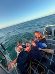 Coast Guard Station San Juan boat crew rescues three boaters from the water after they were forced to abandon their vessel that was taking on a water, approximately one nautical mile north of San Juan Harbor, July 28, 2025.  The Coast Guard boat crew worked with a Puerto Rico Police Marine unit to bring the boaters and the distressed vessel to safe harbor. (U.S. Coast Guard photo)