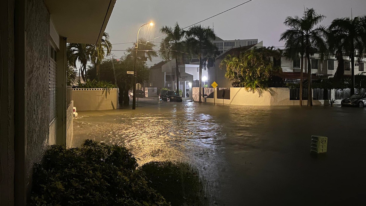 Floodwaters cover a residential street at night.