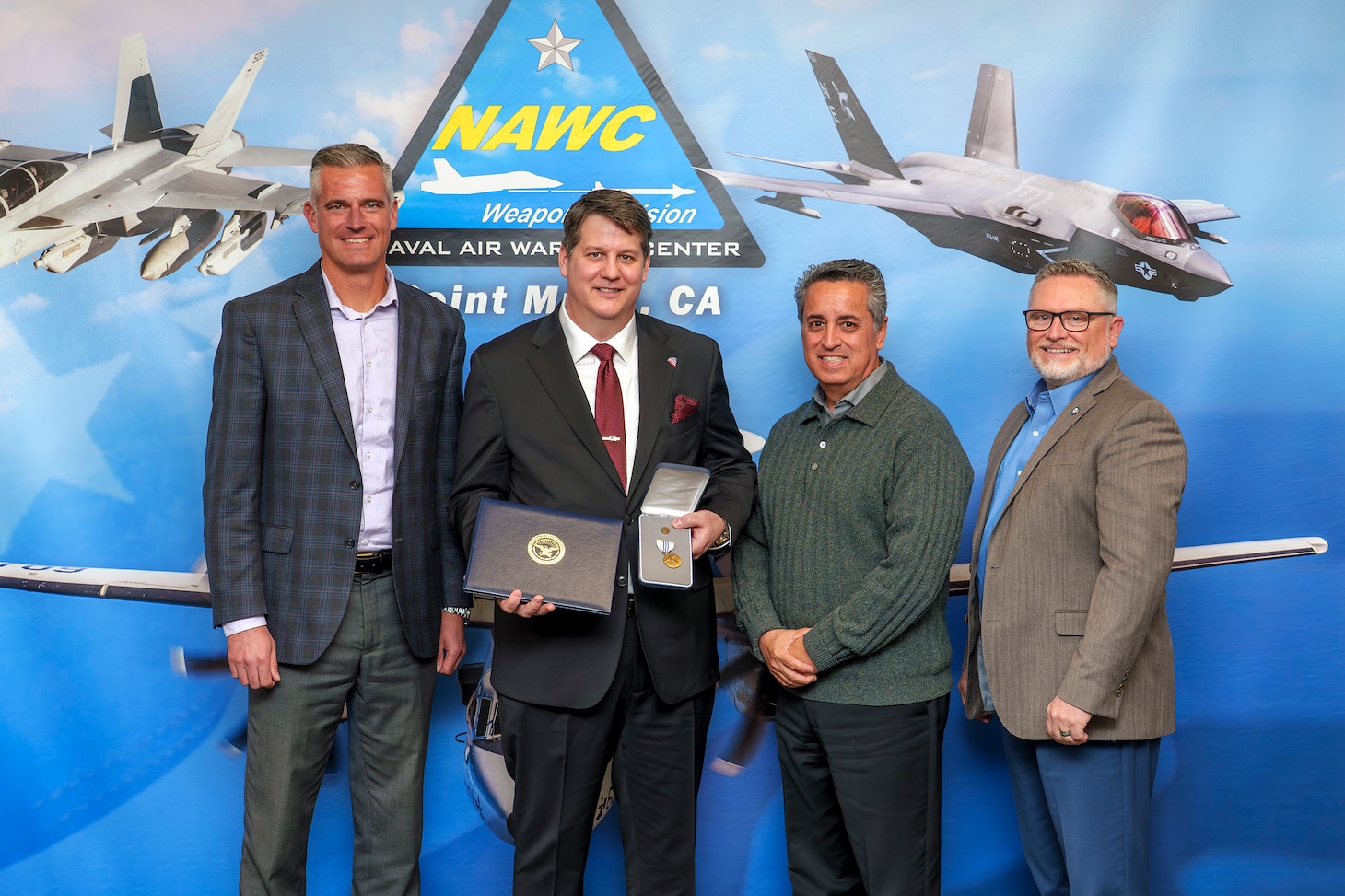 Clint Stammer (holding medal), F-35 Joint Program Office Electronic Attack & Countermeasures lead, poses with Pat Schuett (far left), Gerardo Garcia (second from right), and Tom Dowd (far right) following an award ceremony at Point Mugu, California, April 1. Stammer received the Office of the Secretary of Defense Exceptional Civilian Service medal, the highest honor awarded to career Department of Defense civilians.