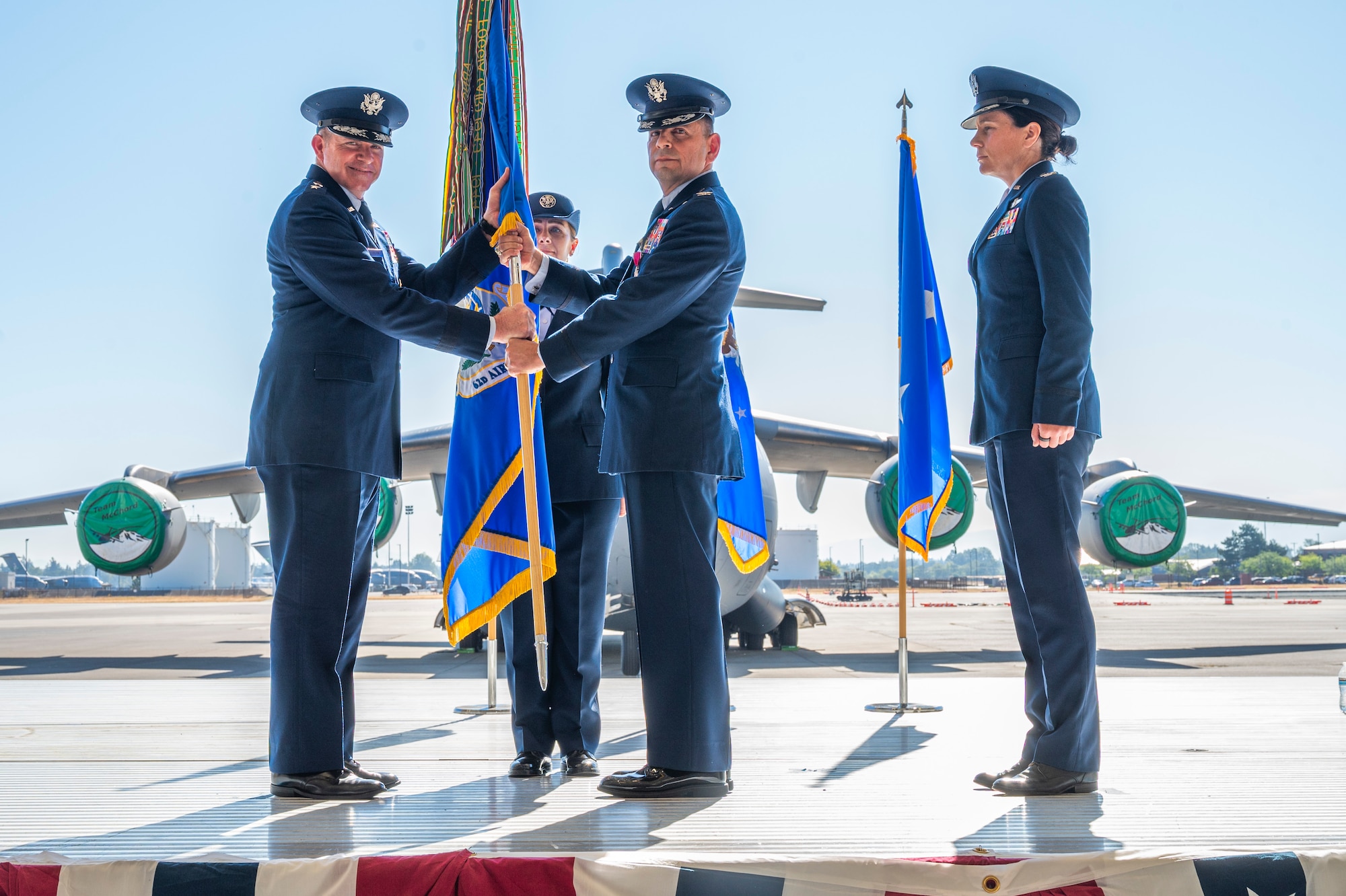 U.S. Air Force Col. Sergio Anaya, center, outgoing 62d Airlift Wing commander, relinquishes command to Maj. Gen. Charles Bolton, Eighteenth Air Force commander, left, during a change of command ceremony at Joint Base Lewis-McChord, Washington, July 29, 2025.