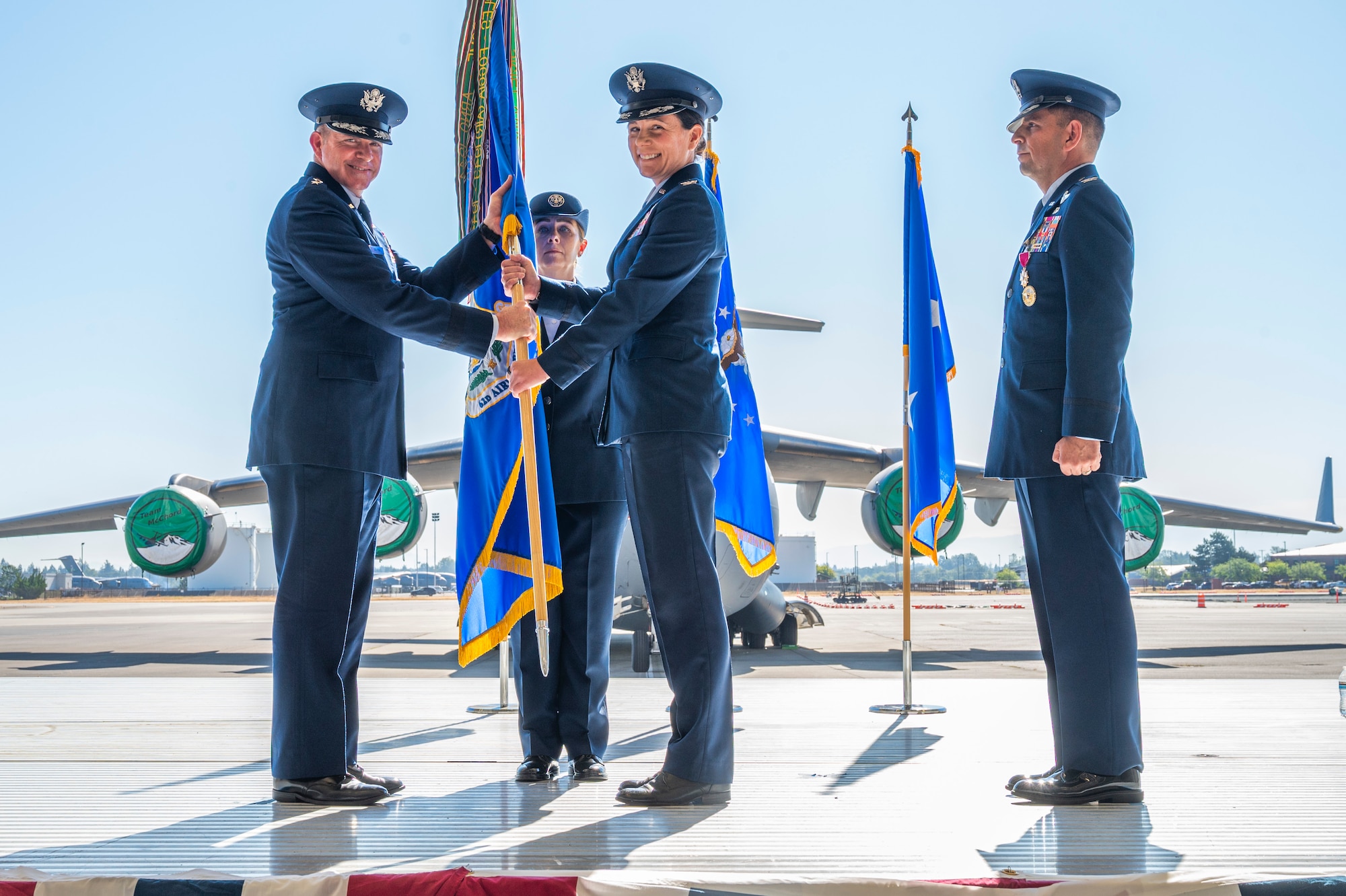 U.S. Air Force Col. Jessica Regni, center, incoming 62d Airlift Wing commander, assumes command from Maj. Gen. Charles Bolton, Eighteenth Air Force commander, left, during a change of command ceremony at Joint Base Lewis-McChord, Washington, July 29, 2025.