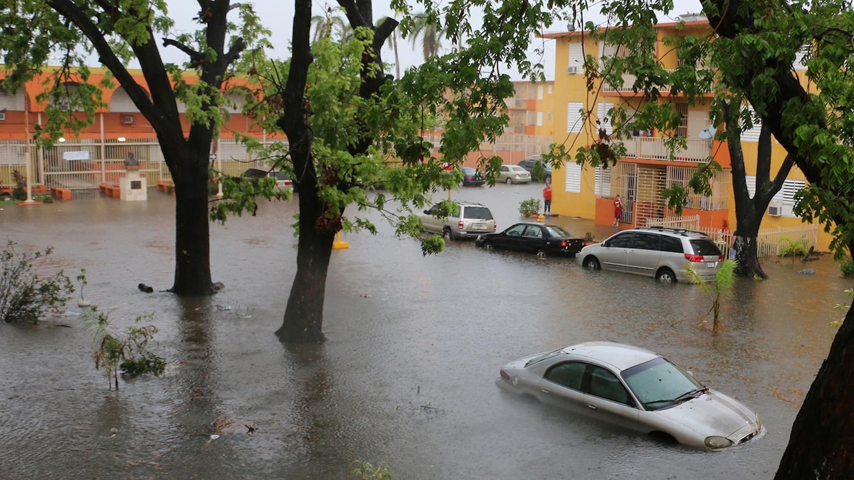 In an apartment complex parking lot, cars are flooded above their wheels.
