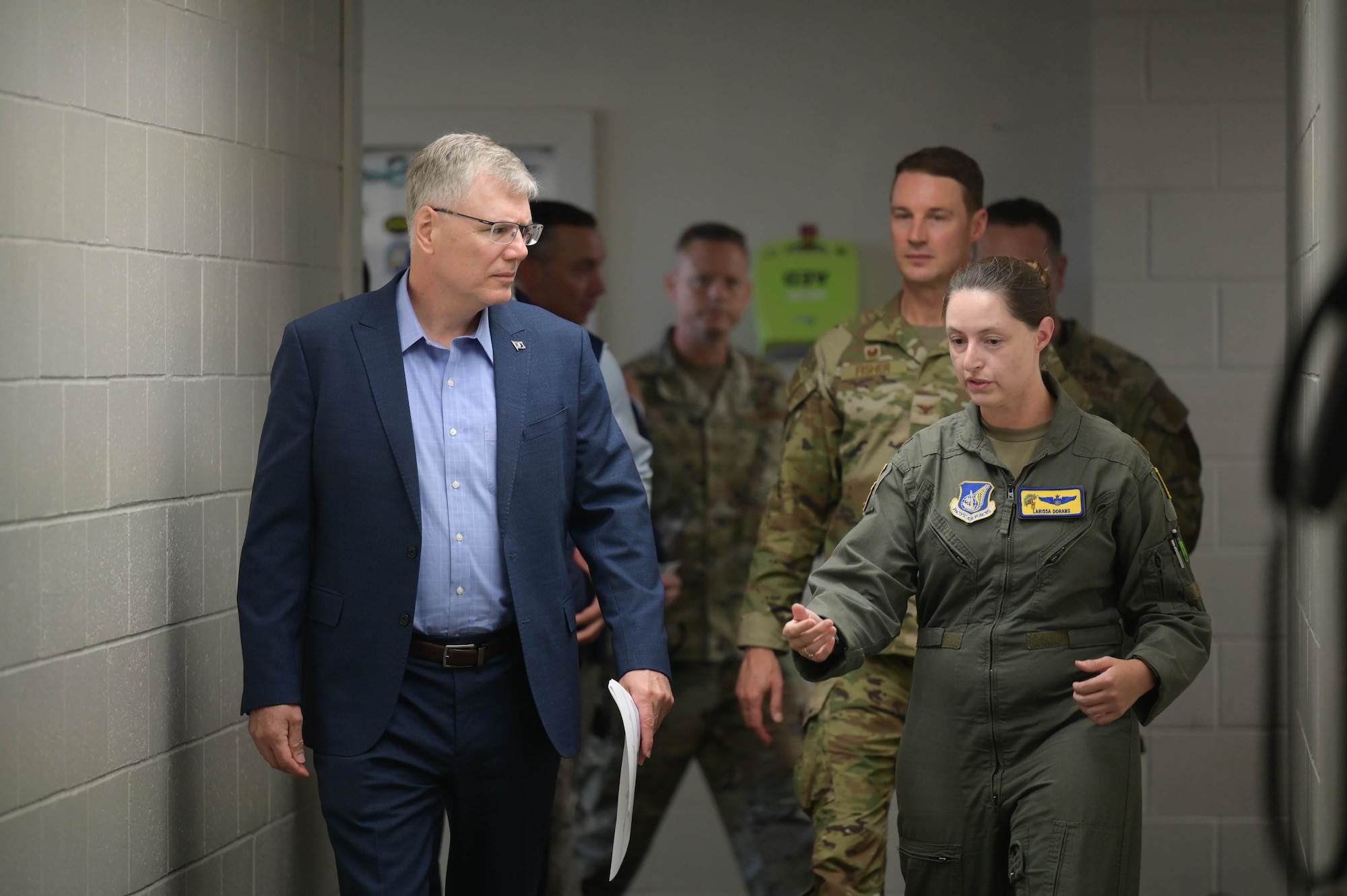 Secretary of the Air Force walks with Airmen down a hallway.