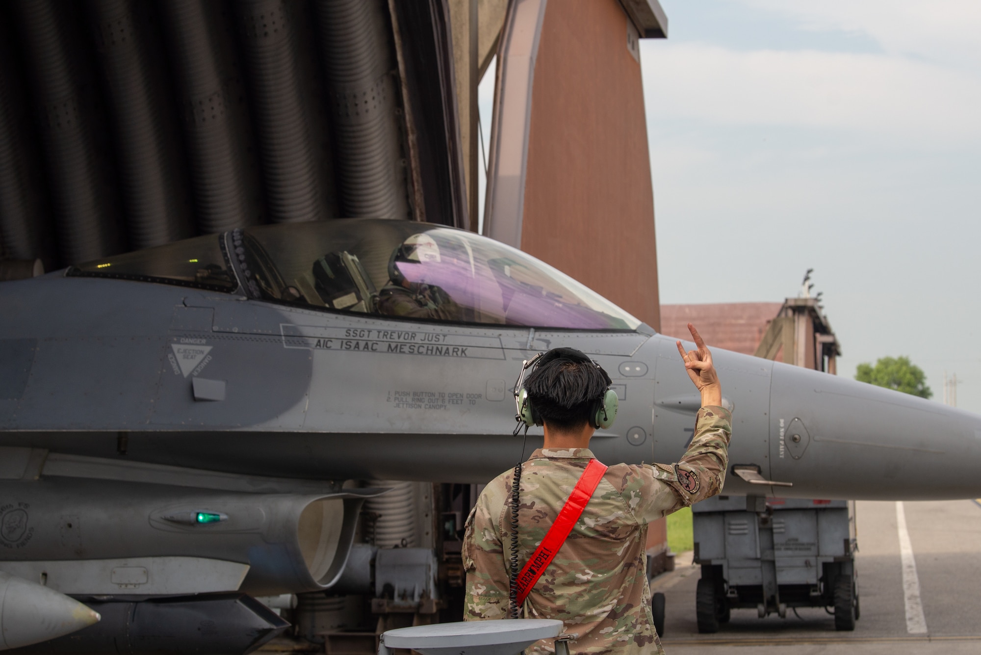 A maintainer gives a squadron hand gesture to a pilot as he departs for takeoff.