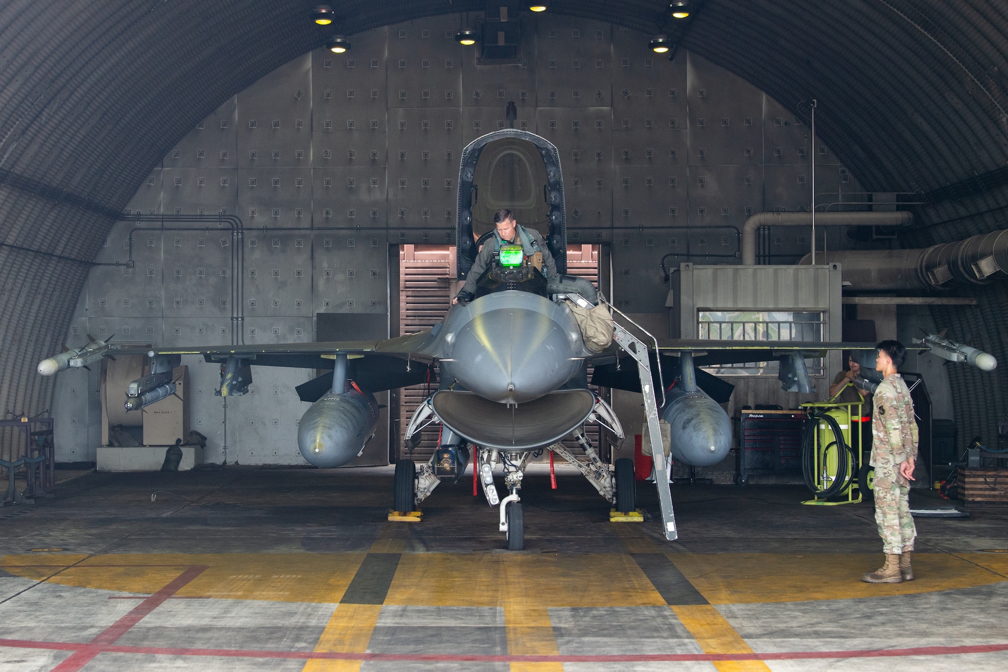 A pilot climbs into the cockpit of an F-16.