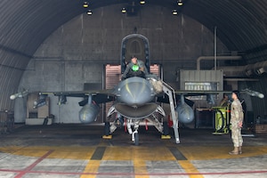 A pilot climbs into the cockpit of an F-16.