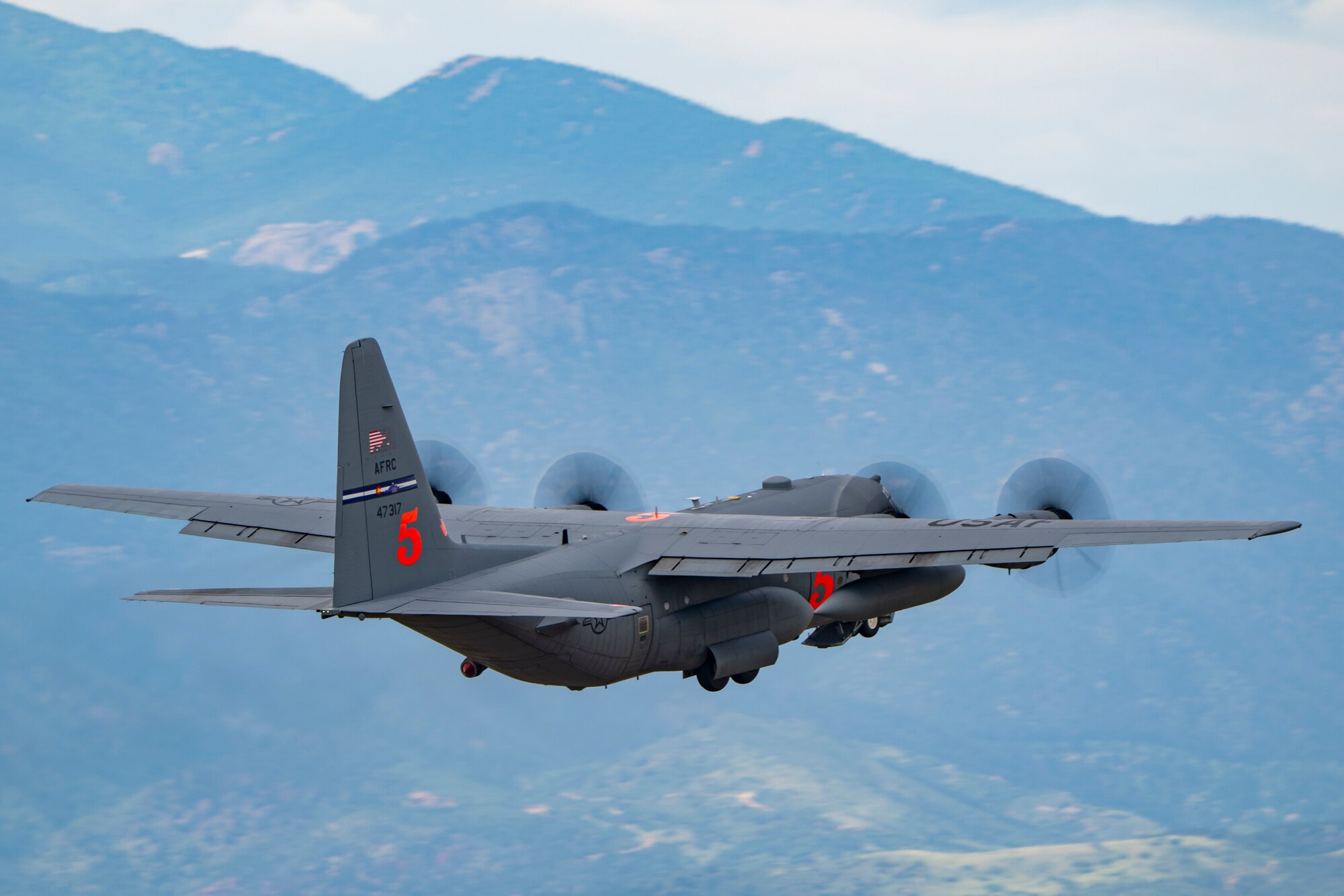 An aircraft taking off with a mountain range in the background.