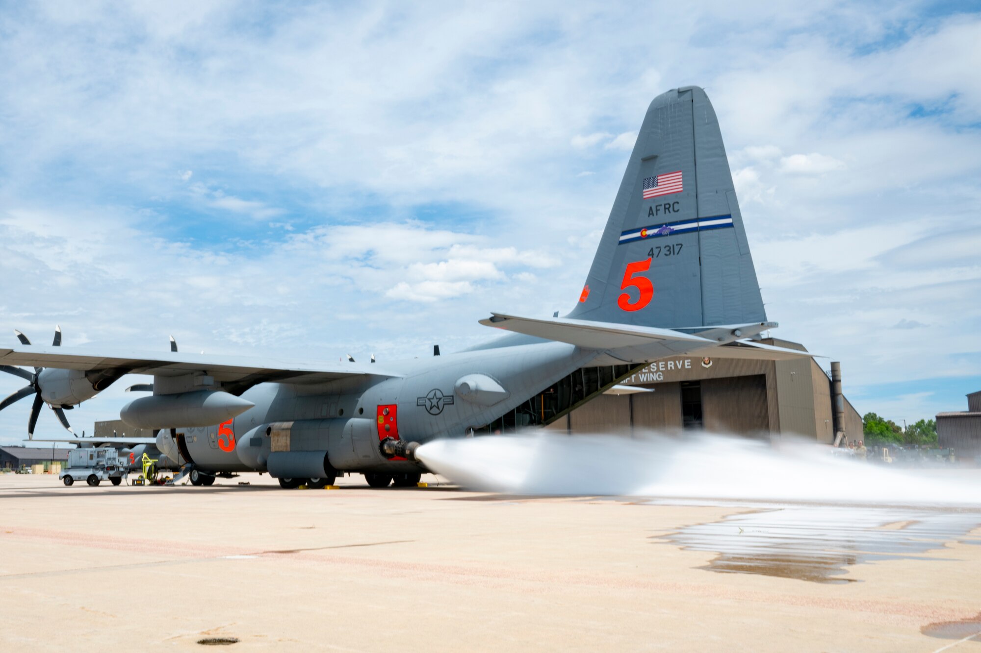 A military aircraft blasting a jet of water from the side.