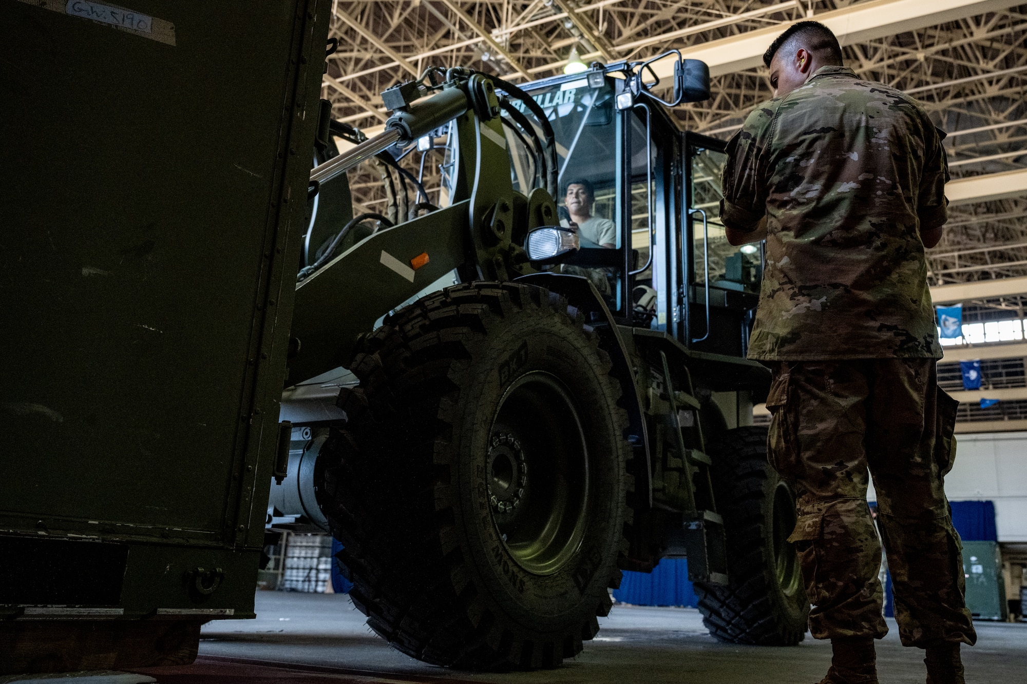 U.S. Air Force Staff Sgt. Noam Naiman, 730th Air Mobility Squadron lead joint inspector, guides a forklift driven by Tech. Sgt. Adrian Diaz, 35th Logistics Readiness Squadron air transportation function noncommissioned officer in charge, to lower cargo during exercise Resolute Force Pacific (REFORPAC) 2025