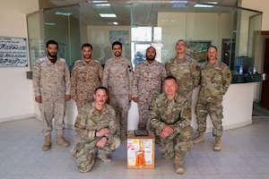 Four U.S. Air Force and four Royal Saudi Air Force service members pose for a photo with a box.