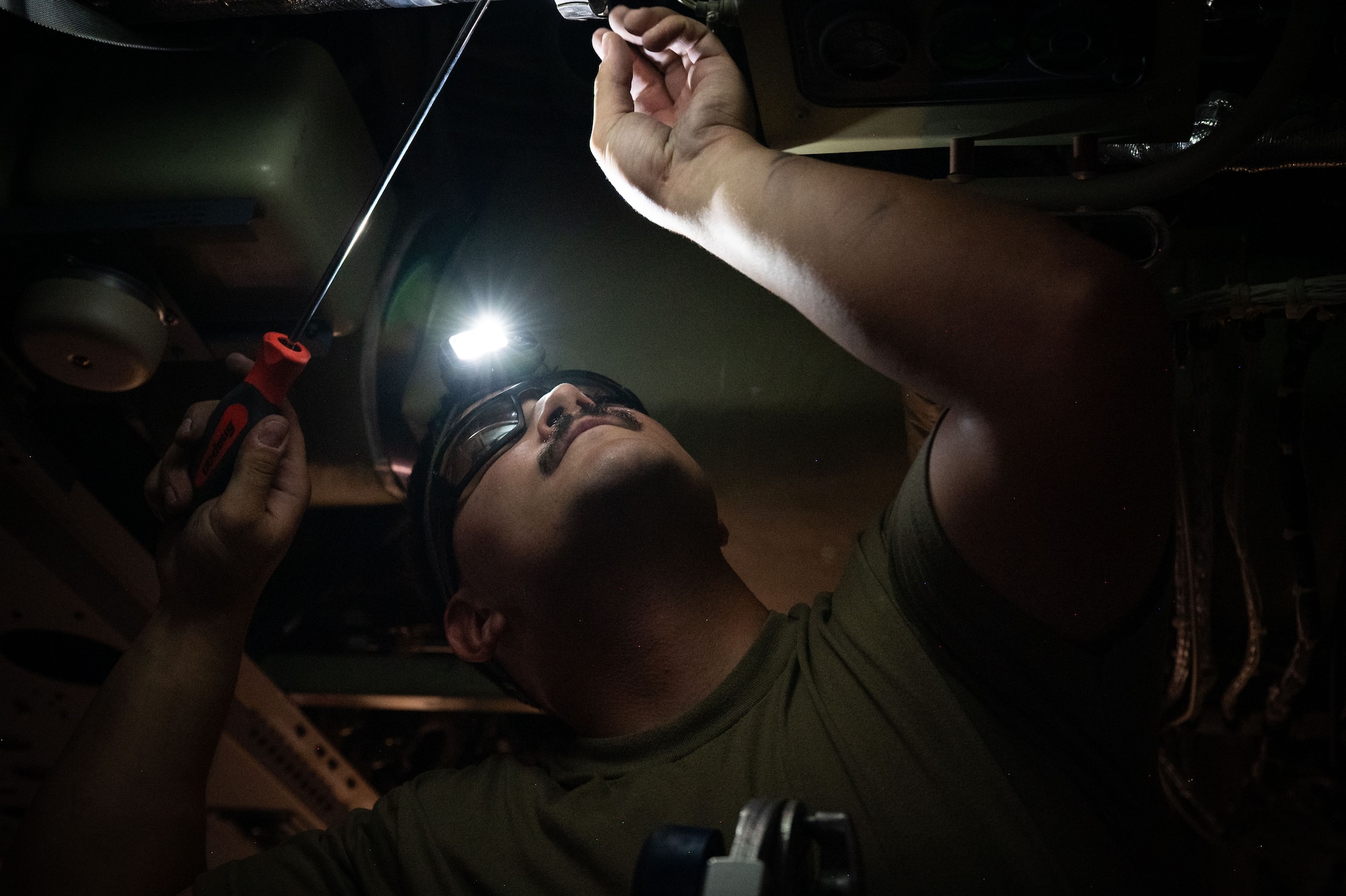 A U.S. Airman installs a part from inside an aircraft
