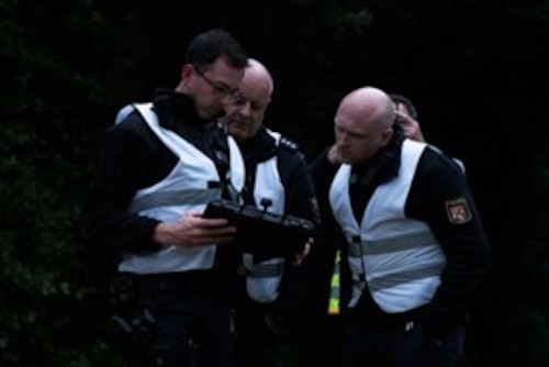 German polizei members look at a handheld screen.