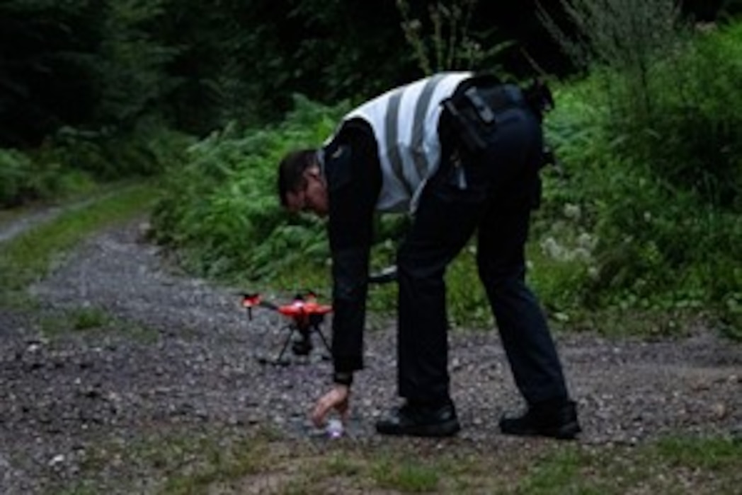 A German polizei member sets up a drone on a gravel road.