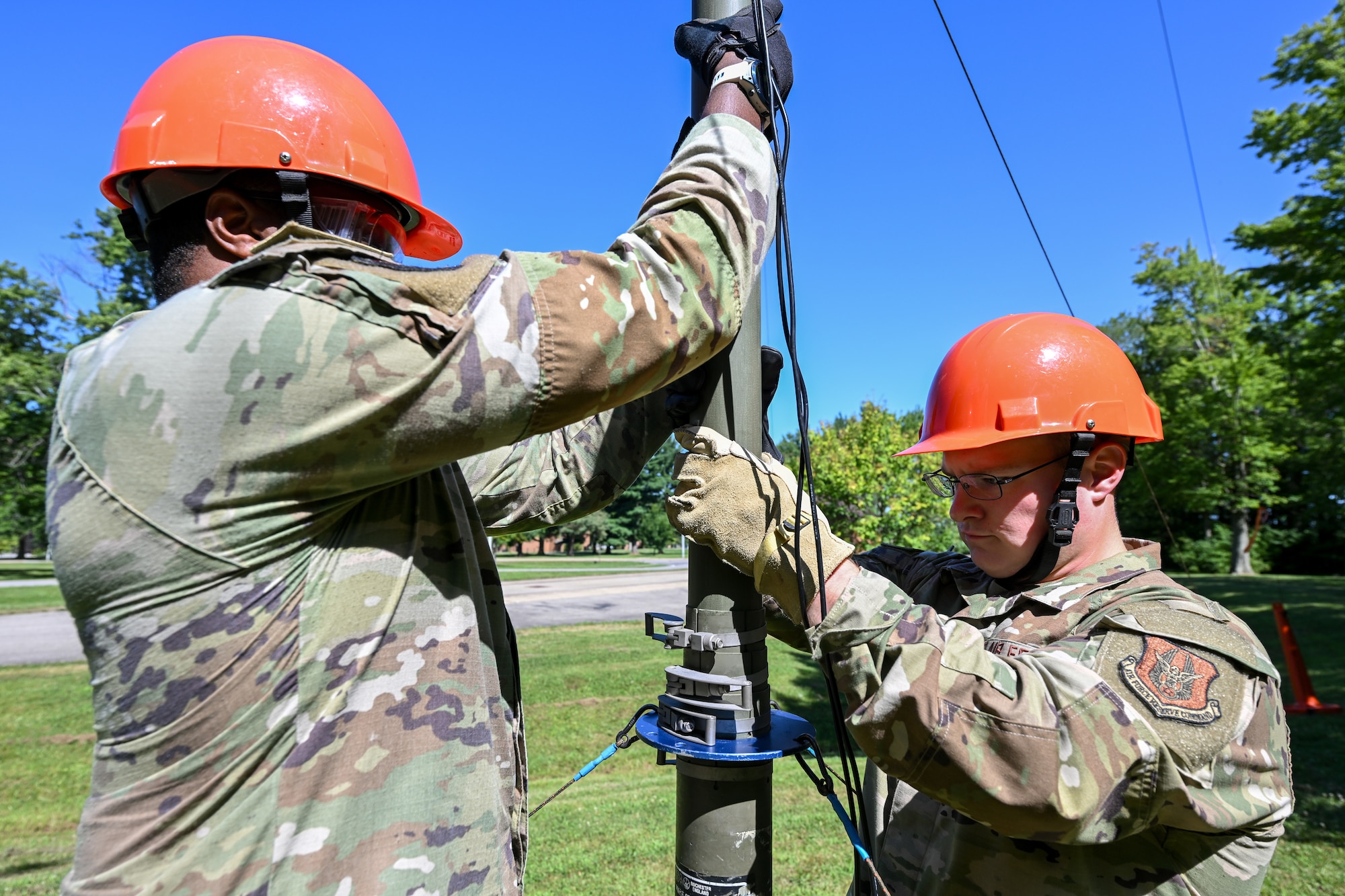 Tech. Sgt. Malik Flowers and Staff Sgt. Jack Claus, 910th Communications Squadron Reserve Airmen, lower a high-frequency radio antenna during the U.S. Army Network Enterprise Technology Command High-Frequency Skills Competition at Youngstown Air Reserve Station, Ohio, July 23, 2025.