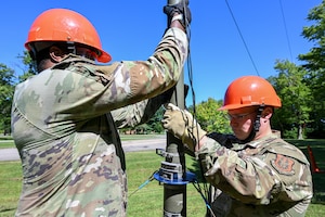 Tech. Sgt. Malik Flowers and Staff Sgt. Jack Claus, 910th Communications Squadron Reserve Airmen, lower a high-frequency radio antenna during the U.S. Army Networks Command High-Frequency Skills Competition at Youngstown Air Reserve Station, Ohio, July 23, 2025. The competition is an international exercise combining 14 countries and 115 military auxiliary radio systems with 134 teams, putting communications squadron Reserve Airmen’s training to the test.
