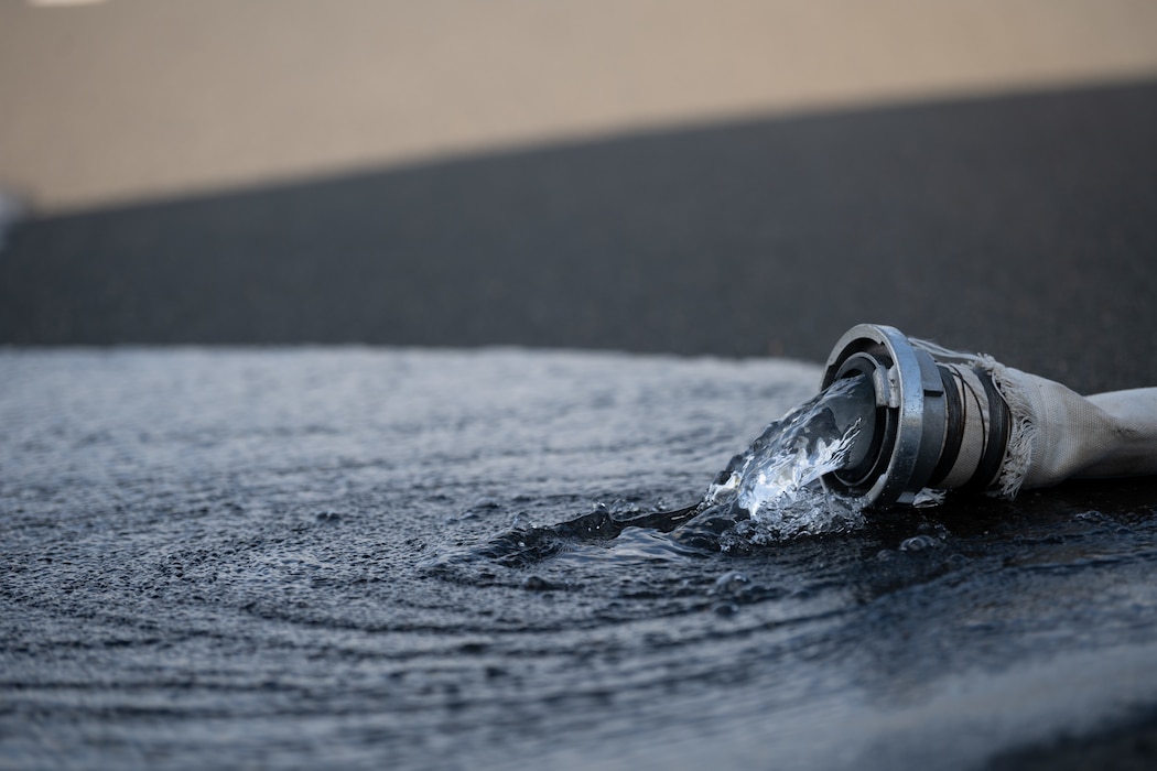 A firehose, used to simulate a fuel spill, pumps water on the ground during a Major Accident Response Exercise at Spangdahlem Air Base, Germany, July 30, 2025. These exercises help ensure that emergency responders are equipped and ready to handle real-world accidents and incidents.