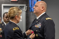 Brig. Gen. Paige M. Jennings, Office of Joint Chiefs of Staff Manpower and Personnel director, presents a Legion of Merit to Col. Ralph M. “Mac” Crum, U.S. Army Financial Management Command finance officer, during Crum’s retirement ceremony at the Maj. Gen. Emmett J. Bean Federal Center in Indianapolis Nov. 26, 2024. Crum most recently served as USAFMCOM’s chief of staff and served four combat tours during his career. (U.S. Army photo by Brad Staggs)