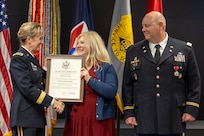 Brig. Gen. Paige M. Jennings, Office of Joint Chiefs of Staff Manpower and Personnel director, presents a certificate of appreciation to Kristine Crum as Col. Ralph M. “Mac” Crum, U.S. Army Financial Management Command finance officer, looks on during the colonel’s retirement ceremony at the Maj. Gen. Emmett J. Bean Federal Center in Indianapolis Nov. 26, 2024. Crum most recently served as USAFMCOM’s chief of staff and served four combat tours during his career. (U.S. Army photo by Brad Staggs)