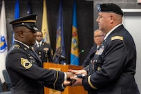 Sgt. 1st Class Deterrance Brown, U.S. Army Financial Management Command senior FM systems instructor, presents an American Flag to Col. Ralph M. “Mac” Crum, USAFMCOM finance officer, during Crum’s retirement ceremony at the Maj. Gen. Emmett J. Bean Federal Center in Indianapolis Nov. 26, 2024. Crum most recently served as USAFMCOM’s chief of staff and served four combat tours during his career. (U.S. Army photo by Brad Staggs)