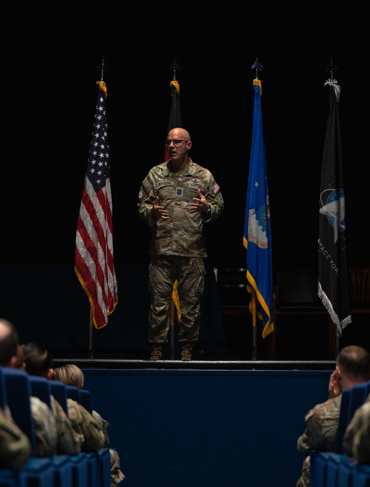 The Chief stands on stage mid-sentence as seen from the walkway below