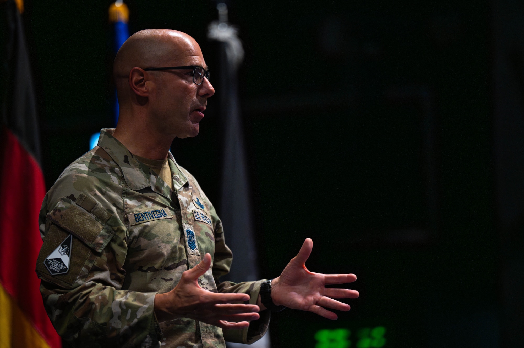 The Chief gestures to the audience while on stage in an auditorium