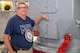A person wearing a United States Navy t-shirt poses for a photo next to a military asset.