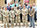 A group of Military and civilian health leaders posing on the steps of the Alexandria VA Hospital,