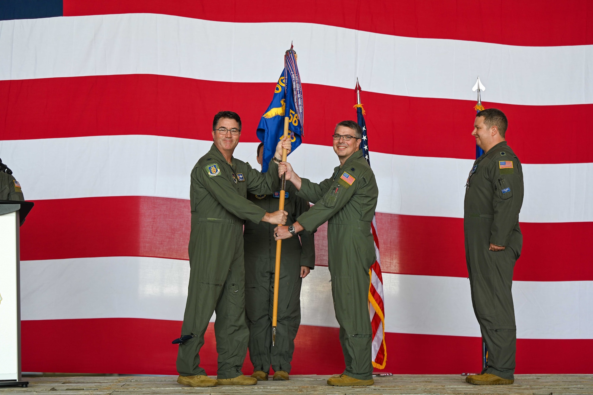U.S. Air Force Col. John Masterson, 97th Operations Group commander, passes the 56th Air Refueling Squadron (ARS) guidon to Lt. Col. John Cockburn, 97th 56th ARS commander, at Altus Air Force Base, Oklahoma, June 9, 2025. The guidon was passed to Cockburn to signify the change of command for the 56th ARS. (U.S. Air Force photo by Airman 1st Class Jonah Bliss)