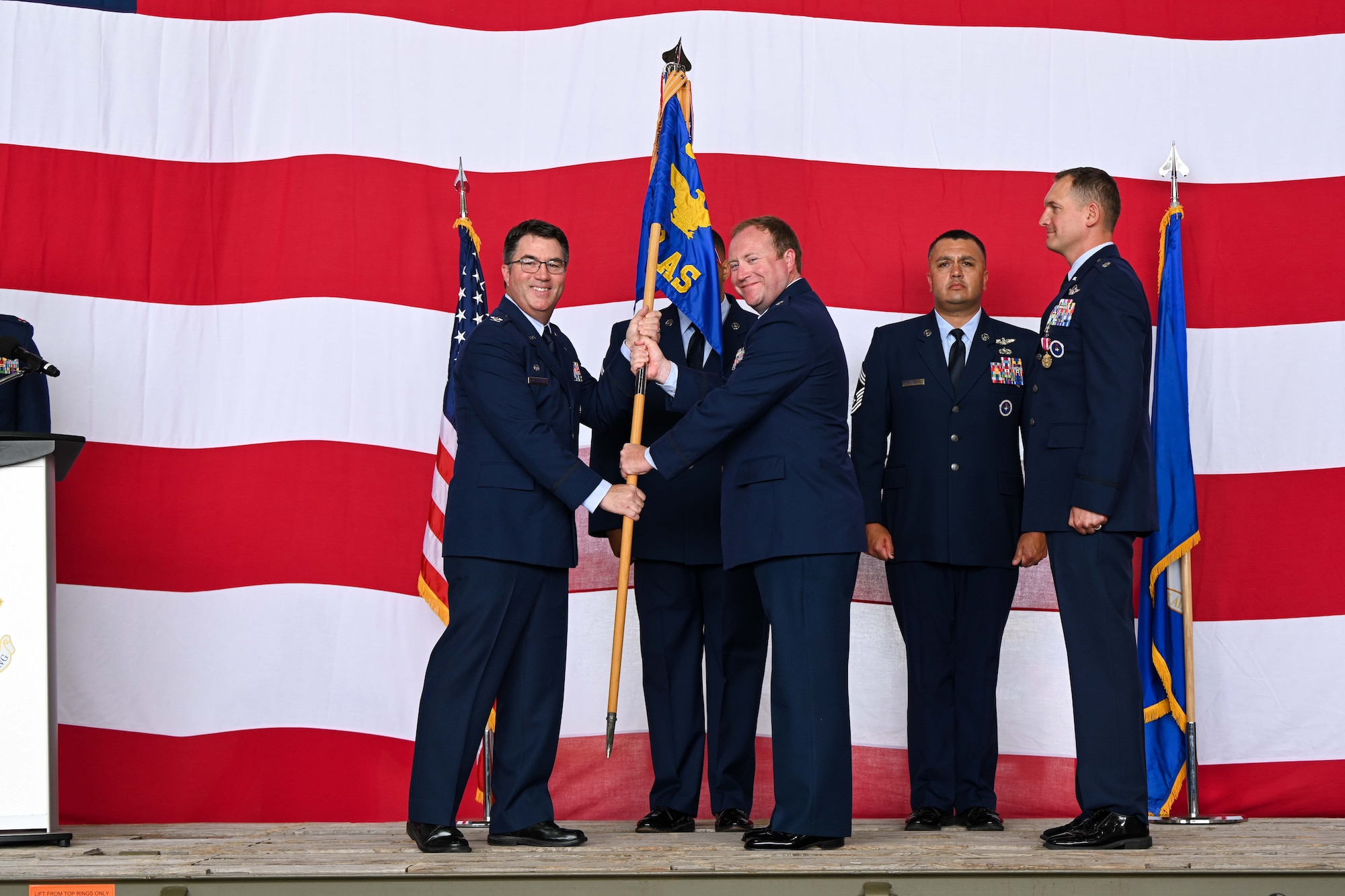 U.S. Air Force Col. John Masterson, 97th Operations Group commander, passes the 58th Airlift Squadron (AS) guidon to Lt. Col. Jonathan Taylor, 58th AS commander, at Altus Air Force Base, Oklahoma, June 10, 2025. The guidon was passed to Cockburn to signify the change of command for the 58th AS. (U.S. Air Force photo by Airman 1st Class Jonah Bliss)