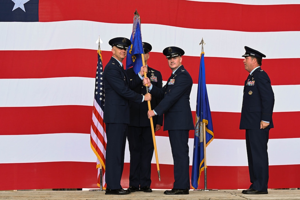 U.S. Air Force Col. Jeff Marshall, 97th Air Mobility Wing commander, passes the 97th Operations Group (OG) guidon to Col. Robert Bittner Jr., 97th OG commander, at Altus Air Force Base, Oklahoma, June 13, 2025. The guidon was passed to Bittner to signify the change of command for the 97th OG. (U.S. Air Force photo by Airman 1st Class Lauren Torres)