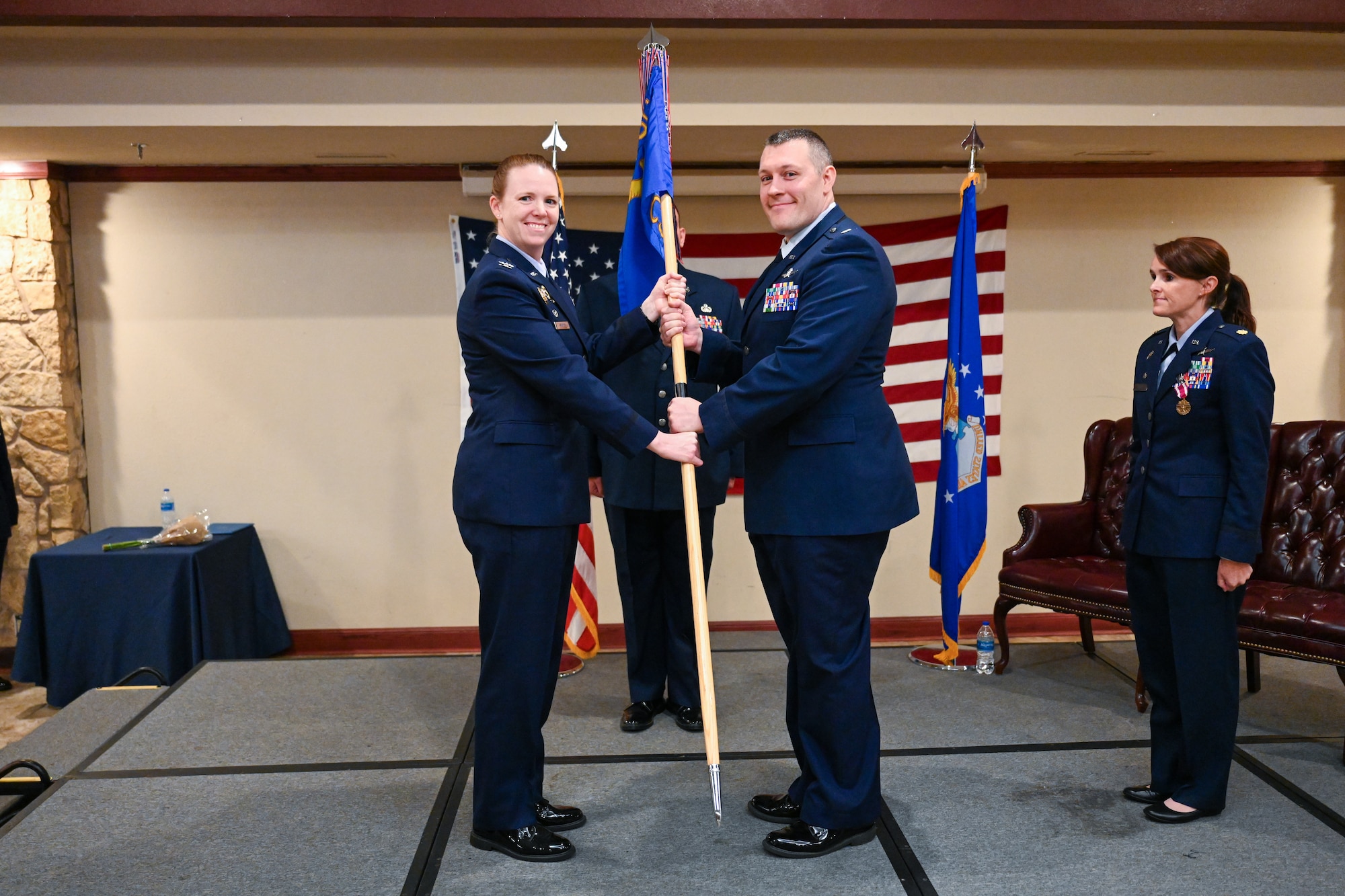 U.S. Air Force Col. Amanda Knotts, 97th Mission Support Group commander, passes the 97th Communications Squadron (CS) guidon to Lt. Col. Dane Jansson, 97th CS commander, at Altus Air Force Base, Oklahoma, June 18, 2025. The guidon was passed to Jansson to signify the change of command for the 97th CS. (U.S. Air Force photo by Airman 1st Class Nathan Langston)