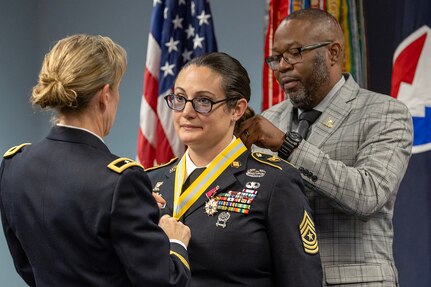 Brig. Gen. Paige M. Jennings, Office of Joint Chiefs of Staff Manpower and Personnel director, left, and retired Command Sgt. Maj. Gennaro Penn, U.S. Army Finance Corps Association president, right, present Sgt. Maj. Julie D. Harris, U.S. Army Financial Management Command Operations senior enlisted advisor, with a Maj. Gen. Nathan Towson Regimental Medallion during Harris’ retirement ceremony at the Maj. Gen. Emmett J. Bean Federal Center in Indianapolis Nov. 25, 2024. Harris retired from the U.S. Army after more than 22 years of service. (U.S. Army photo by Mark R. W. Orders-Woempner)