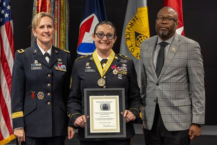 Brig. Gen. Paige M. Jennings, Office of Joint Chiefs of Staff Manpower and Personnel director, left, and retired Command Sgt. Maj. Gennaro Penn, U.S. Army Finance Corps Association president, right, present Sgt. Maj. Julie D. Harris, U.S. Army Financial Management Command Operations senior enlisted advisor, with a Maj. Gen. Nathan Towson Regimental Medallion during Harris’ retirement ceremony at the Maj. Gen. Emmett J. Bean Federal Center in Indianapolis Nov. 25, 2024. Harris retired from the U.S. Army after more than 22 years of service. (U.S. Army photo by Mark R. W. Orders-Woempner)