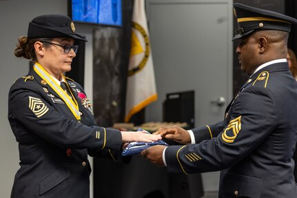 Sgt. 1st Class Deterrance Brown, U.S. Army Financial Management Command senior FM systems instructor, presents an American Flag to Sgt. Maj. Julie D. Harris, U.S. Army Financial Management Command Operations senior enlisted advisor, during Harris’ retirement ceremony at the Maj. Gen. Emmett J. Bean Federal Center in Indianapolis Nov. 25, 2024. Harris retired from the U.S. Army after more than 22 years of service. (U.S. Army photo by Mark R. W. Orders-Woempner)