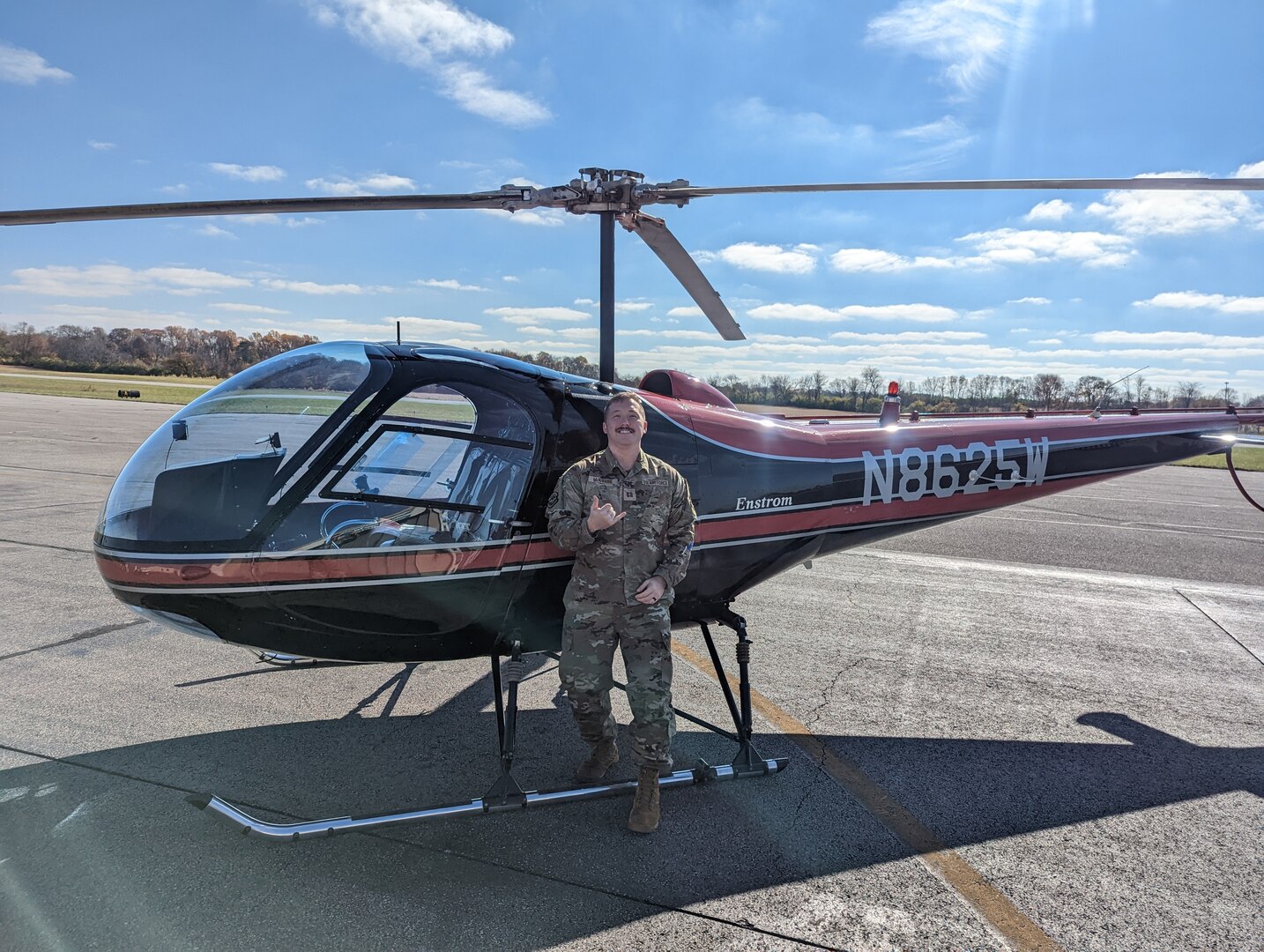 Image of an Airman posing for a photo in front of a helicopter.