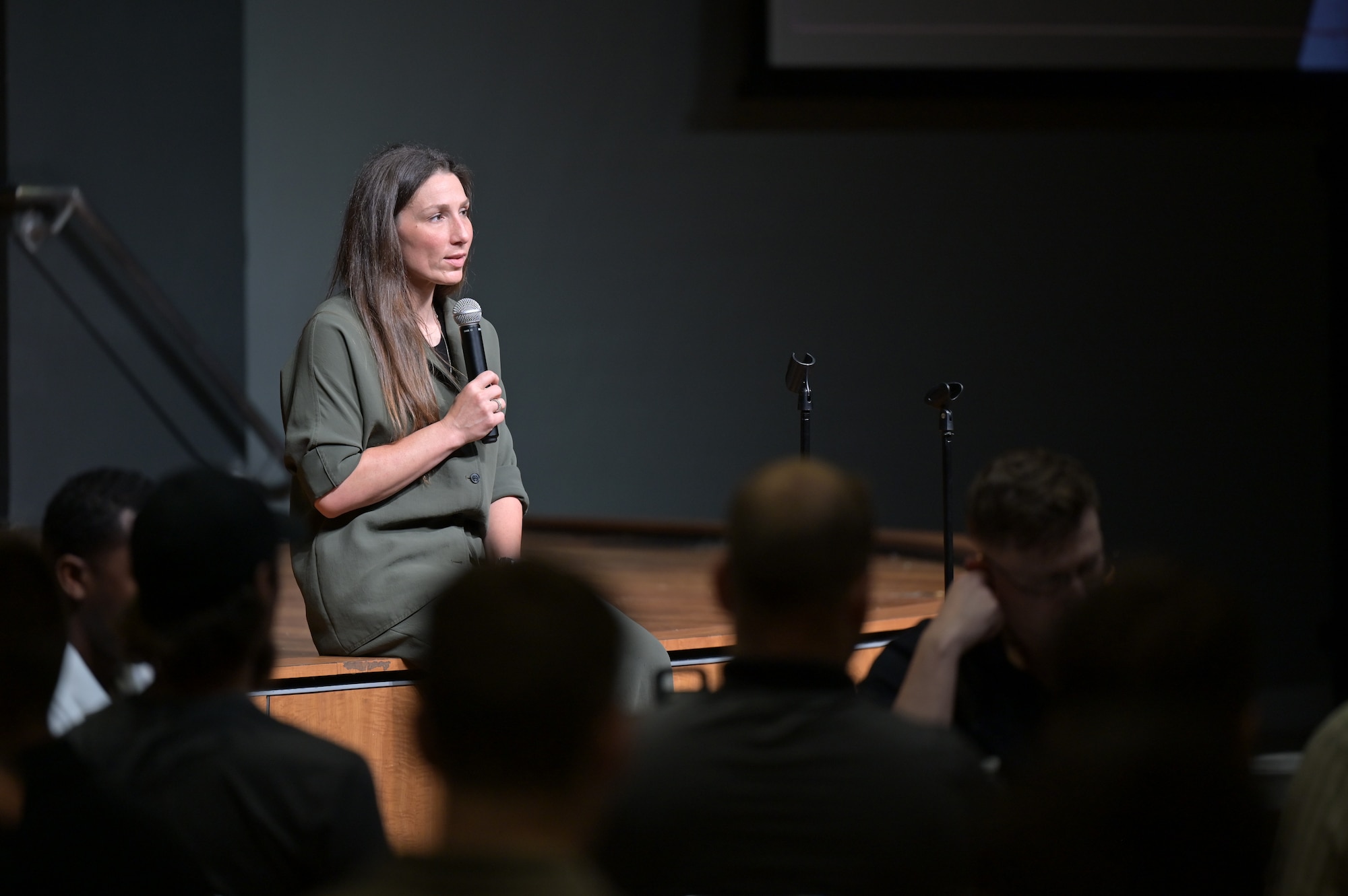 Dr. Nichole Davis sits on the edge of a stage speaking to an attentive audience about mindfulness.