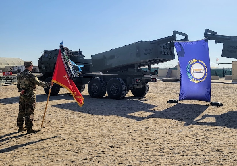 A U.S. Army Soldier assigned to 1st Battalion, 623d Field Artillery Regiment, 138th Field Artillery Brigade bears the guidon in front of formation as their M142 High Mobility Artillery Rocket Systems (HIMARS) display the Kentucky flag.