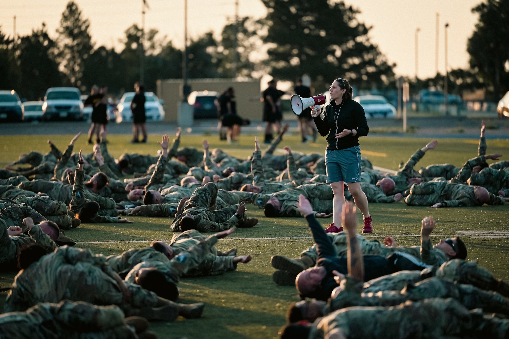 woman speaks to group of airmen working out