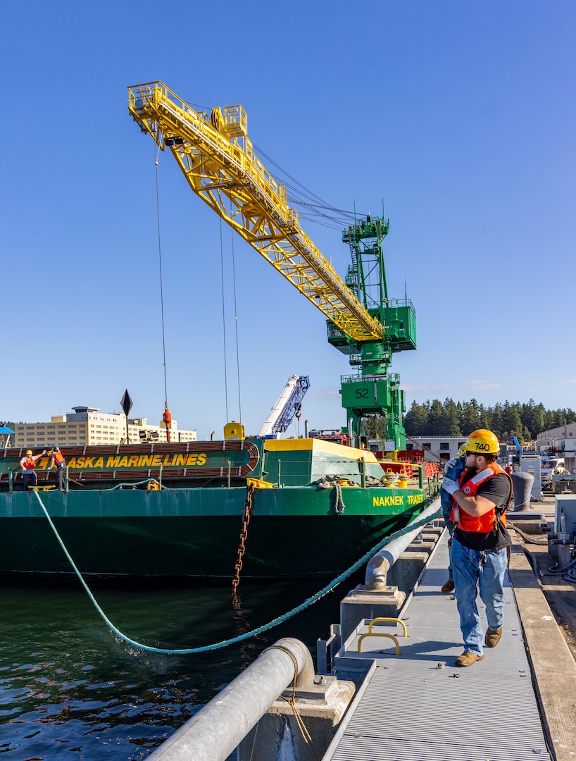 Carlos Murphy, rigger, Code 740, Riggers, helps guide a barge carrying new portal Crane 52 into Pier Bravo at Puget Sound Naval Shipyard & Intermediate Maintenance Facility in Bremerton, Washington. July 14, 2025. (U.S. Navy photo by Wendy Hallmark)