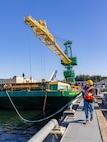 Carlos Murphy, rigger, Code 740, Riggers, helps guide a barge carrying new portal Crane 52 into Pier Bravo at Puget Sound Naval Shipyard & Intermediate Maintenance Facility in Bremerton, Washington. July 14, 2025. (U.S. Navy photo by Wendy Hallmark)